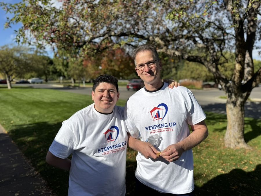 Two walkers in Stepping Up shirts smiling in the park