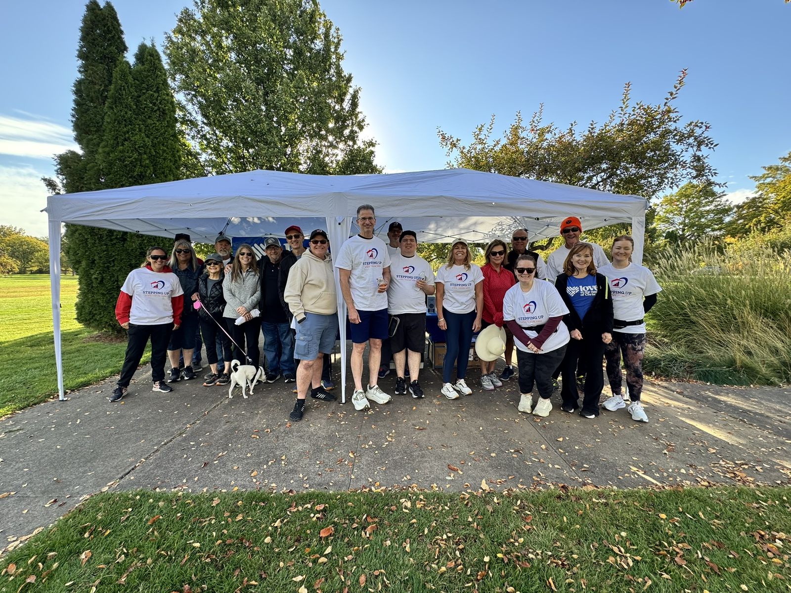 Stepping Up walkers in event shirts gathered under the check-in tent at Ann Morrison Park